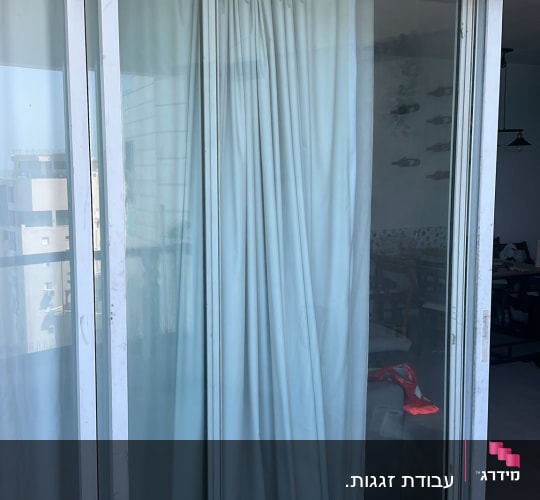 דלת זכוכית עם וילון לבן במרפסת
